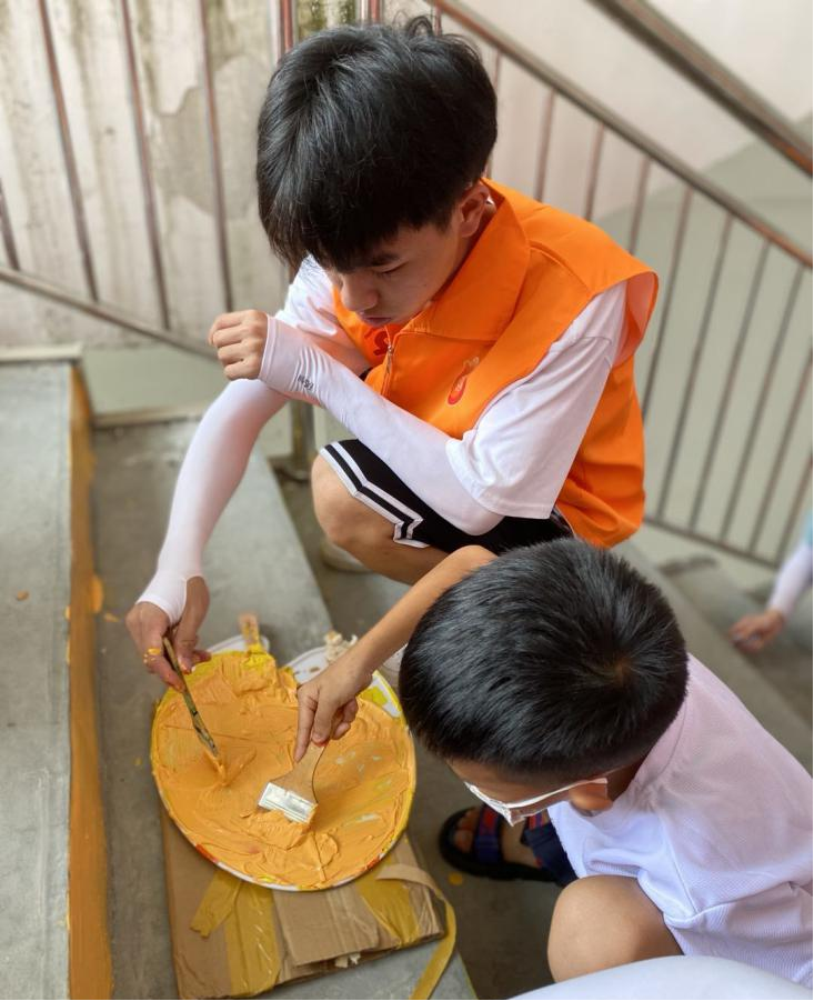 志愿服務(wù)團(tuán)成員與小朋友一起進(jìn)行階梯繪畫