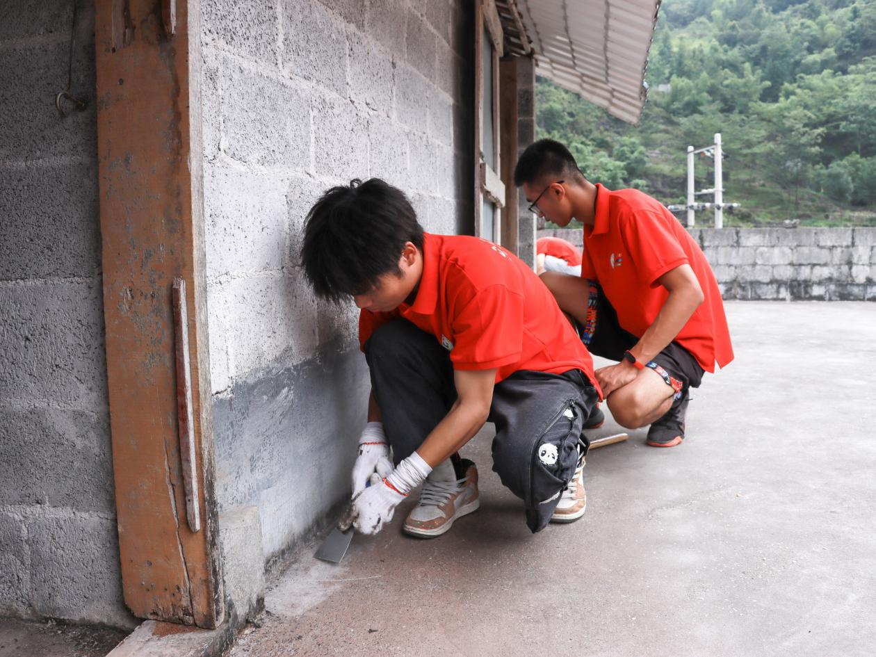 實(shí)踐團(tuán)成員為村民清理墻角漏水裂縫