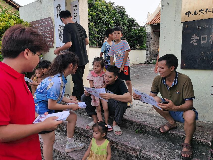 實踐團(tuán)成員在宗祠前發(fā)放宣傳手冊講解龍獅運動