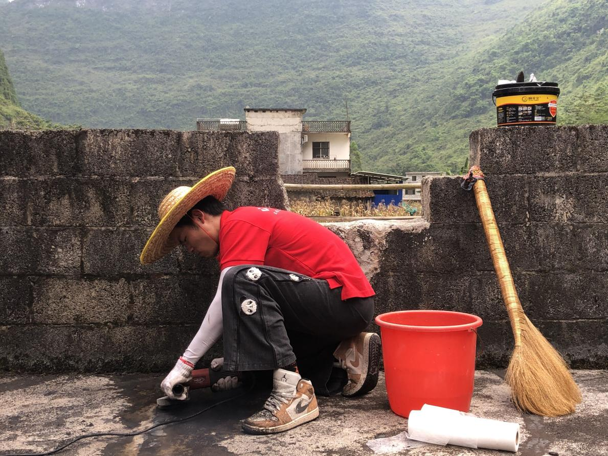 實(shí)踐團(tuán)成員正在對(duì)村民屋頂裂縫處進(jìn)行清理打磨